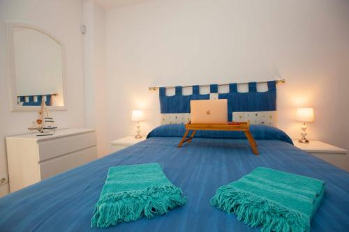 Corralejo Gin 72 Premium في كوراليخو: غرفة نوم مع سرير أزرق مع لاب توب عليها