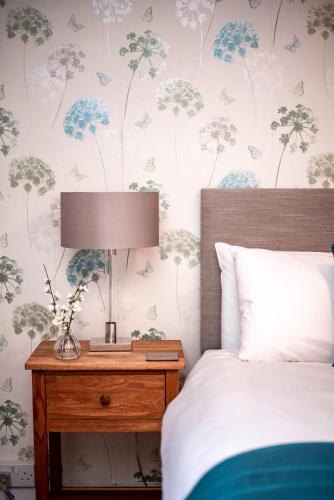 a bedroom with a bed and a table with a lamp at Trivelles Waterhall Country Gatwick Hotel & airport parking in Crawley