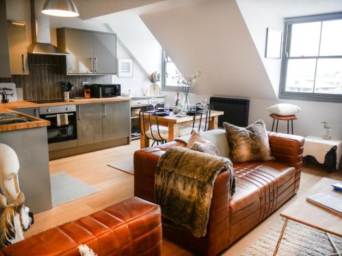 a living room with a couch and a kitchen at Padstow Escapes - Teyr Luxury Penthouse Apartment in Padstow