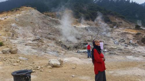 a woman is standing in front of a geyser at TriDwi Homestay in Parakan