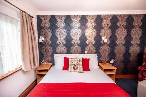 a bedroom with a red and white bed with red pillows at Trivelles Waterhall Country Gatwick Hotel & airport parking in Crawley