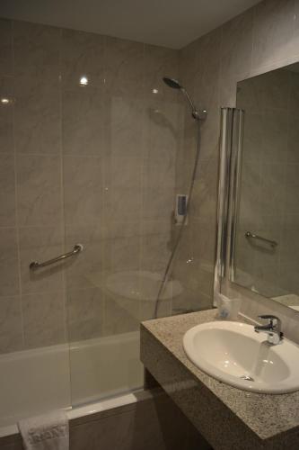 uma casa de banho com um lavatório e uma cabina de duche em vidro. em Hotel Brisa Marina em S'Illot