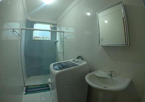 y baño con lavabo, aseo y espejo. en Residencial Margaridas ap 1, en Porto Seguro