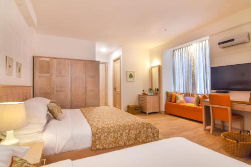 a bedroom with a bed and a television and a couch at The Lynden Grove in Nuwara Eliya