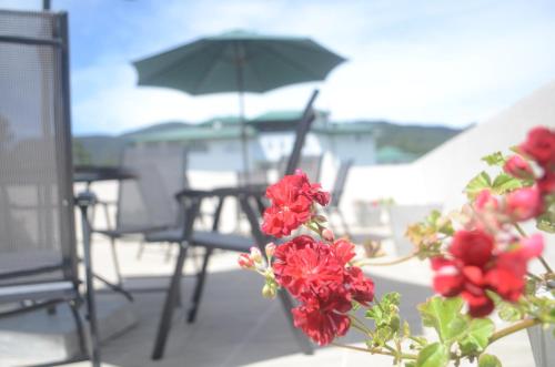 a table and chairs with an umbrella and red flowers at The Lynden Grove in Nuwara Eliya