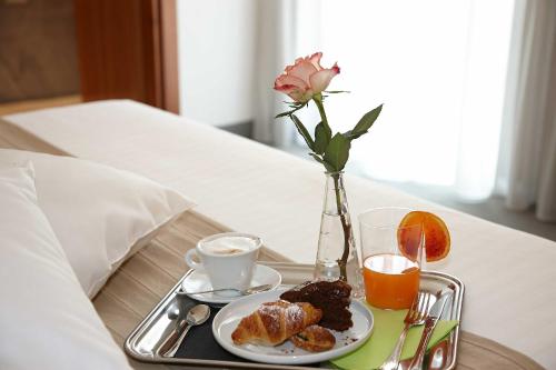 a tray with breakfast foods and a vase with a rose at Vicenza Tiepolo Hotel in Vicenza