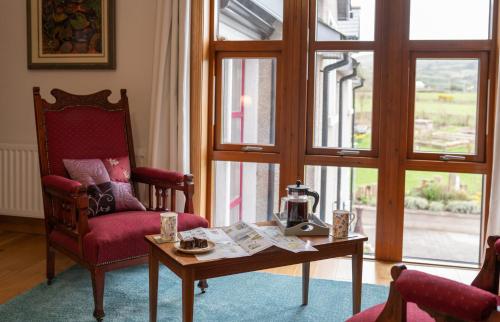 a living room with a coffee table and a chair and windows at BallyCairn House in Larne