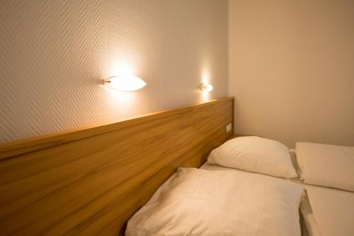 a bed in a room with two lights on the wall at Hotel Gremersdorf - Zum Grünen Jäger in Gremersdorf