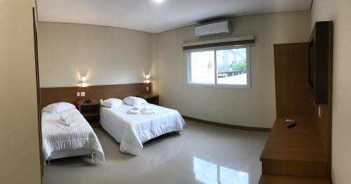 a hotel room with two beds and a window at Ipê Palace Hotel in Adamantina