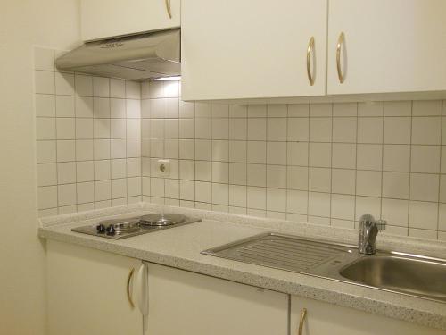 eine Küchentheke mit einem Waschbecken und einem Spiegel in der Unterkunft NewLivingHome Residenzhotel Hamburg in Hamburg