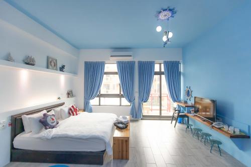sypialnia z niebieskimi ścianami, łóżkiem i telewizorem w obiekcie Kimoji B&B w mieście Huxi