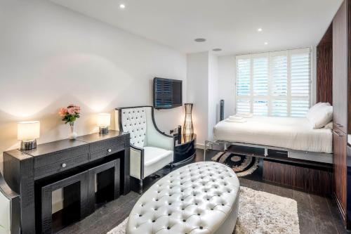 um quarto com uma cama, uma cadeira e uma lareira em ALTIDO Luxury Studio in Chelsea, close to Sloane Square and Victoria station em Londres