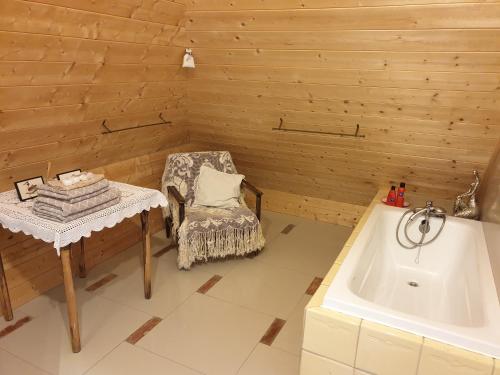 a bathroom with a tub and a chair and a table at DOM GOŚCINNY PTASZARNIA - NATURA-Free PARKING in Świnoujście