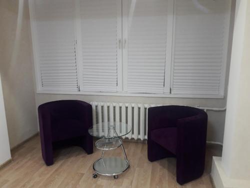 two purple chairs and a glass table in a room at Апартаменты Оболонь in Kyiv