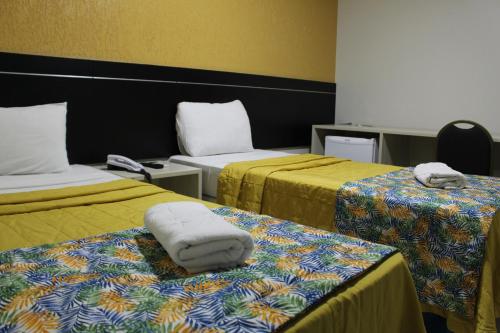 a hotel room with two beds with towels on them at Hotel Cruzeiro in Arcoverde