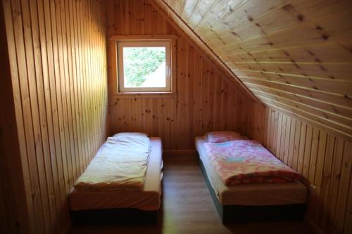 2 camas en una habitación pequeña con ventana en Domki nad jeziorem w Karłowicach, en Karłowice