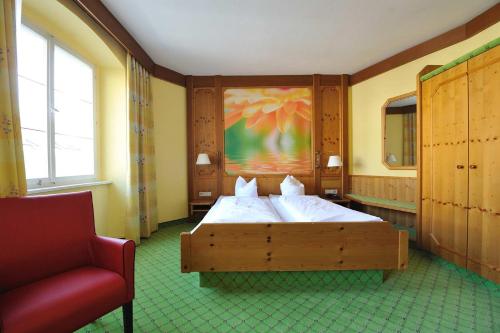 Hotel Gasthof Stift في لينداو: غرفة نوم بسرير وكرسي احمر
