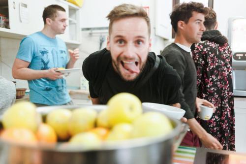 a man sticking his tongue out in front of a bowl of apples at Sant Jordi Hostels Lisbon in Lisbon