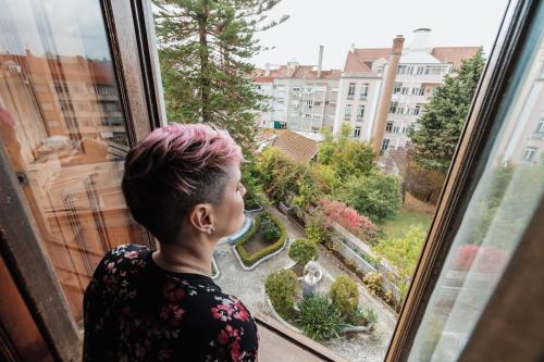 a woman looking out of a window at a garden at Sant Jordi Hostels Lisbon in Lisbon