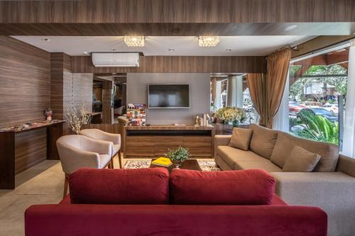 a living room with a couch and a tv at Hotel Fioreze Centro in Gramado