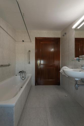 a bathroom with a bath tub and a sink at Hotel Las Vegas in Burgos