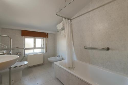 a bathroom with a tub and a toilet and a sink at Hotel Las Vegas in Burgos