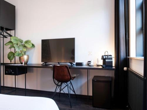 a desk with a monitor and a chair in a room at MABI City Centre in Maastricht