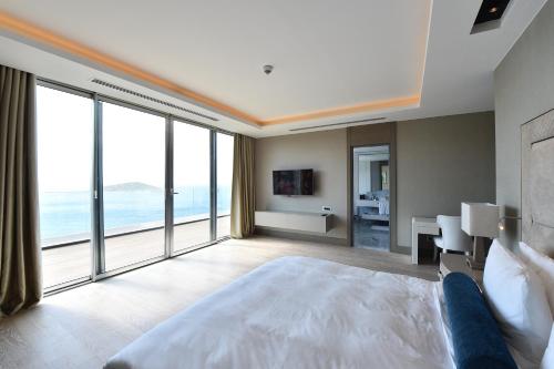 a bedroom with a large bed and large windows at Sirene Luxury Hotel Bodrum in Yalıkavak