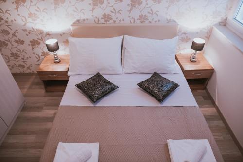 a bed with two pillows on it with two lamps at Pool Apartments Lucija in Novalja
