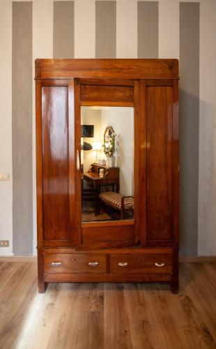 a wooden cabinet with a mirror in a room at La Colonna (Historic Centre) in Lucca