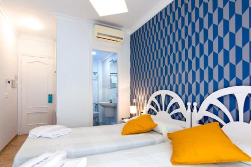 a bedroom with two beds with yellow pillows at Hostal Luna de Nerja in Nerja