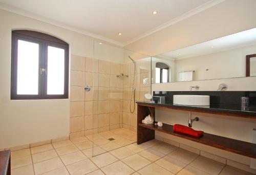 a bathroom with a shower and a sink and a mirror at Montrose Guesthouse in Somerset West