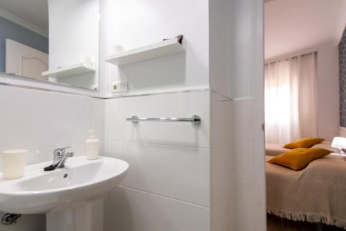 a white bathroom with a sink and a bed at Hostal Luna de Nerja in Nerja