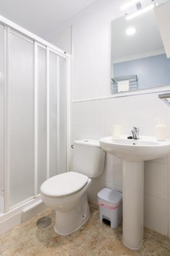 a white bathroom with a toilet and a sink at Hostal Luna de Nerja in Nerja