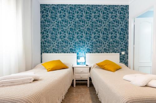 two beds in a room with a blue wall at Hostal Luna de Nerja in Nerja