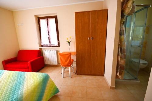 1 dormitorio con silla roja y puerta de cristal en B&b La Nuova Stella, en Perano