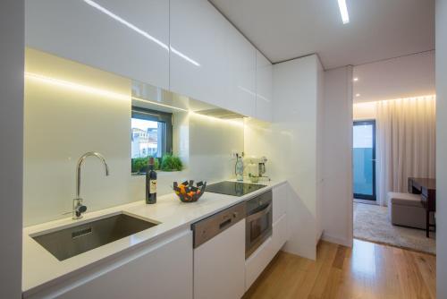a white kitchen with a sink and a counter at Domum in Porto