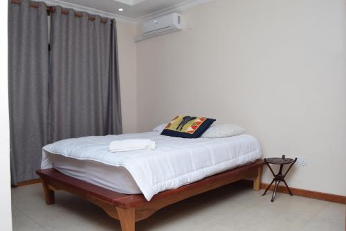 1 dormitorio con 1 cama con sábanas blancas y ventana en Upland Estates Serviced Apartments, en Lusaka