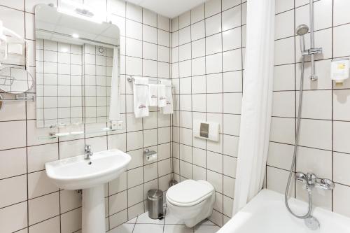 a white bathroom with a toilet and a sink at Geneva Hotel in Sofia