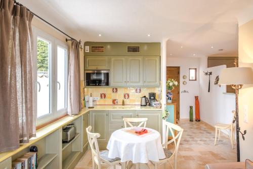une cuisine avec des armoires vertes, une table et des chaises dans l'établissement Orangerie St Paul, à Saint-Paul-de-Vence