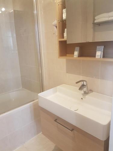 a bathroom with a sink, mirror, and bathtub at Hotel Saint Gothard in Nice