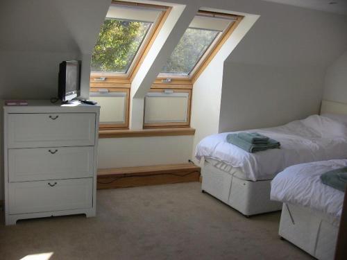 1 dormitorio con 2 camas y 2 ventanas en The Garden Apartment en Dunino