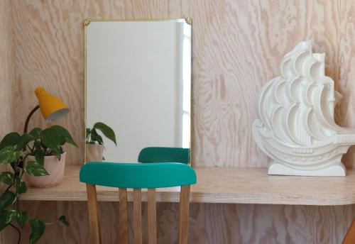 une chaise verte assise sur une étagère devant un miroir dans l'établissement Le Petit Rivage, à La Charité-sur-Loire