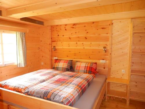 ein Schlafzimmer in einem Blockhaus mit einem Bett in der Unterkunft Kristlisalm in Hopfgarten in Defereggen