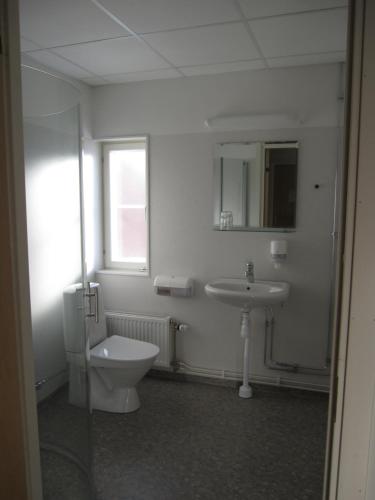a bathroom with a toilet, sink, and tub at Hotell Ramudden in Valbo