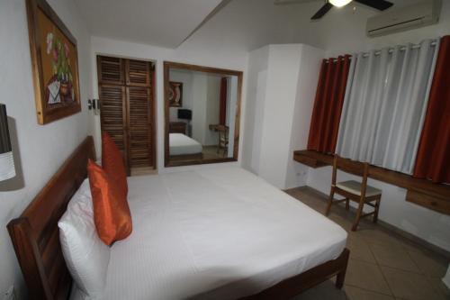 a bedroom with a white bed and a mirror at Albachiara Hotel - Las Terrenas in Las Terrenas