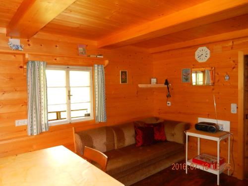 ein Wohnzimmer mit einem Sofa und einer Uhr an der Wand in der Unterkunft Kristlisalm in Hopfgarten in Defereggen