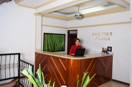 una mujer parada en un mostrador con un portátil en Hotel Bolivar Plaza, en Manizales