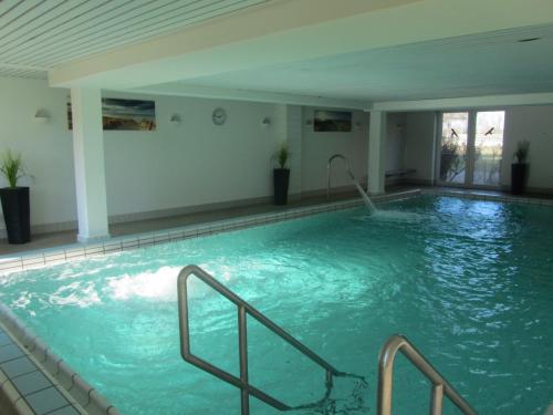 a large swimming pool with blue water in a building at Residenz Albatros in Cuxhaven
