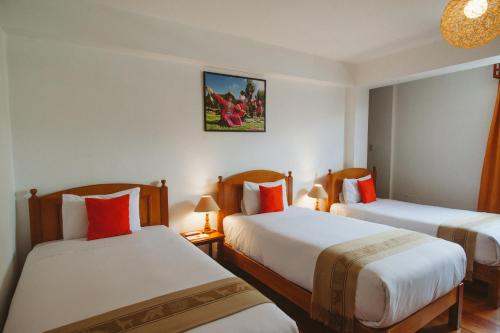 a hotel room with two beds with red pillows at Hotel Monasterio San Pedro in Cusco